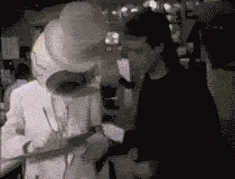 A black and white gif a Resident eyeball signing an autograph and smooching someone. This is from the Toronto interview.